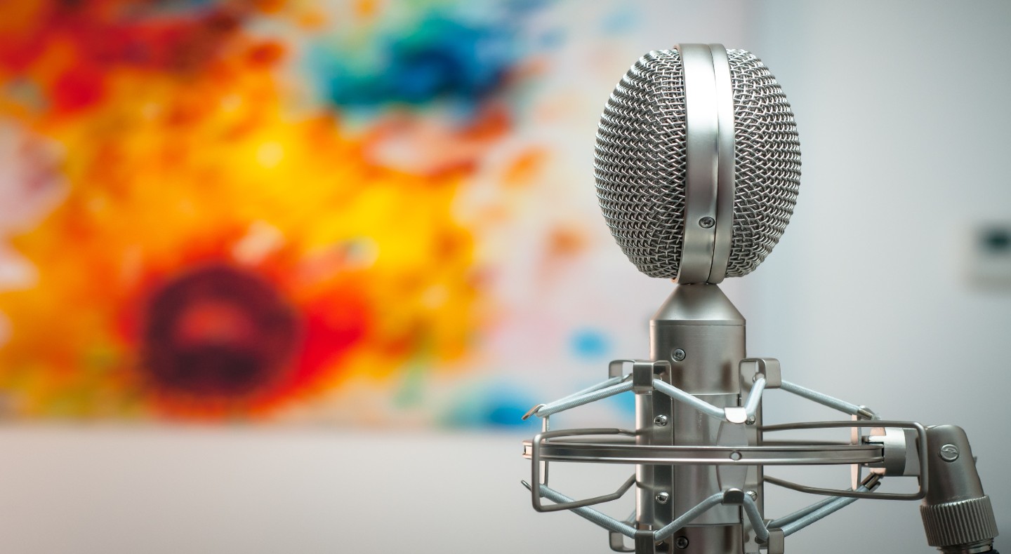 A silver microphone is in front of a colorful piece of modern art.