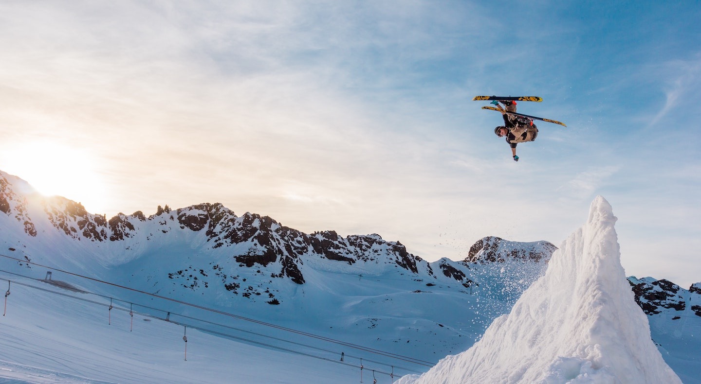 A skier makes a huge jump off a sharp, vertical peak