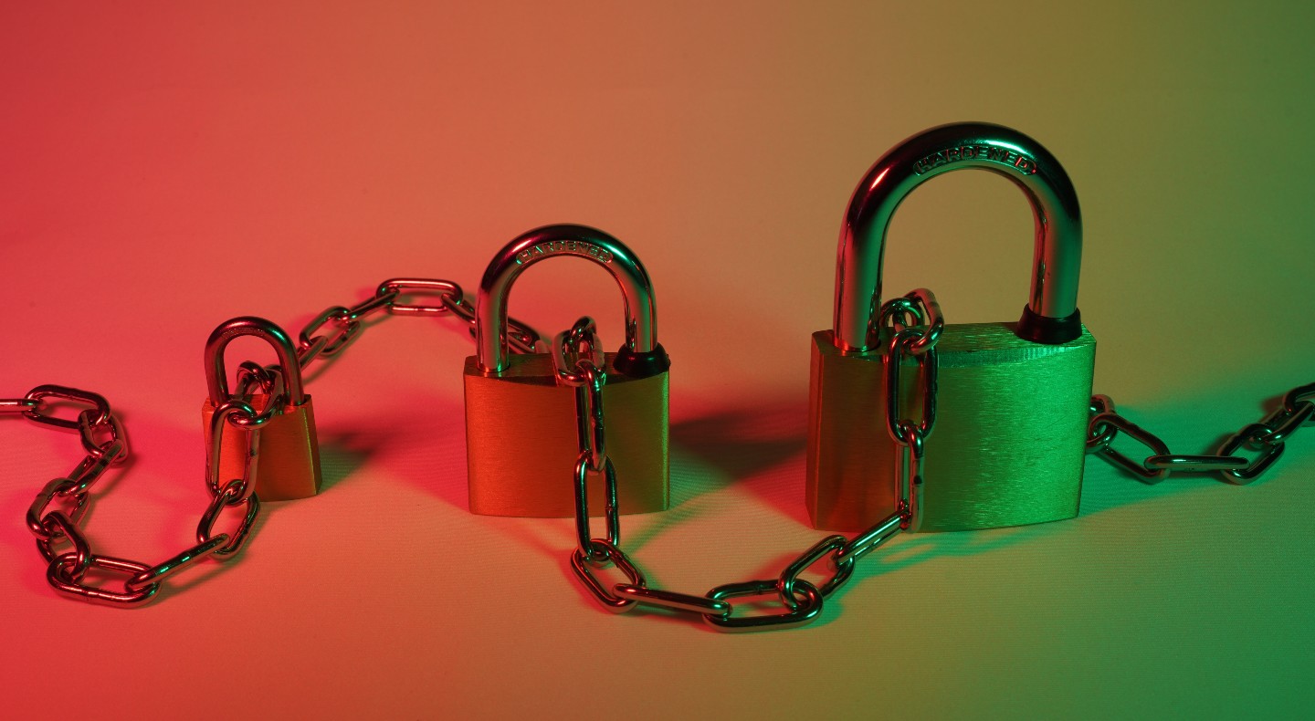 Three padlocks are locked into a chain