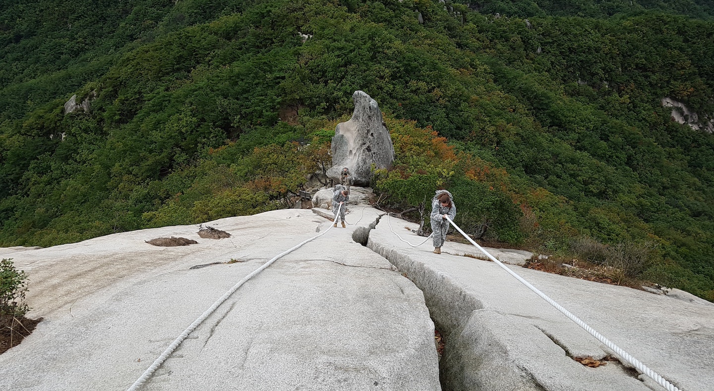 Two people scale a sheer cliff with ropes