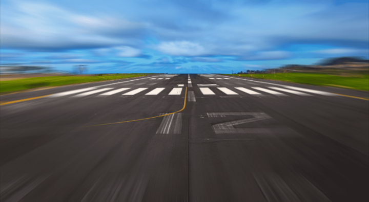 A blurred image of a runway, with a large number 12 on the tarmac.